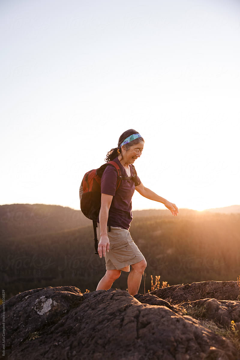 Woman hiking in early morning sunshine on hilltop.