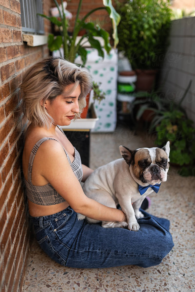 Young woman hugging her french bulldog dog with bow tie at home