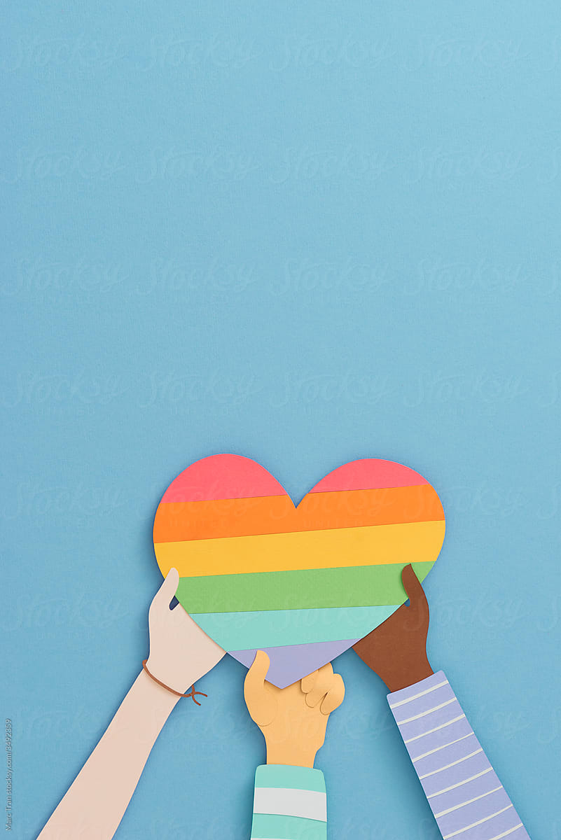 Many hands holding the rainbow heart of LGBT flag