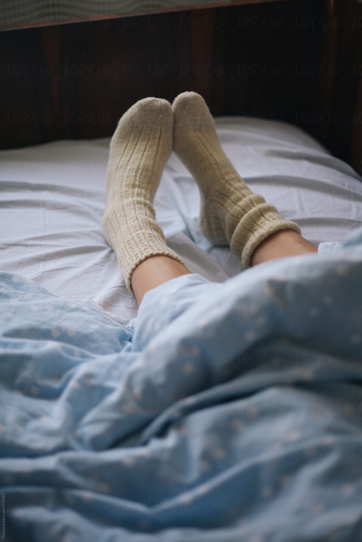 Female legs in cosy winter socks under the sheet - Stock Image - Everypixel