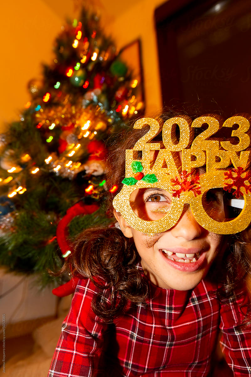 Kid making funny faces with Happy 2023 party glasses