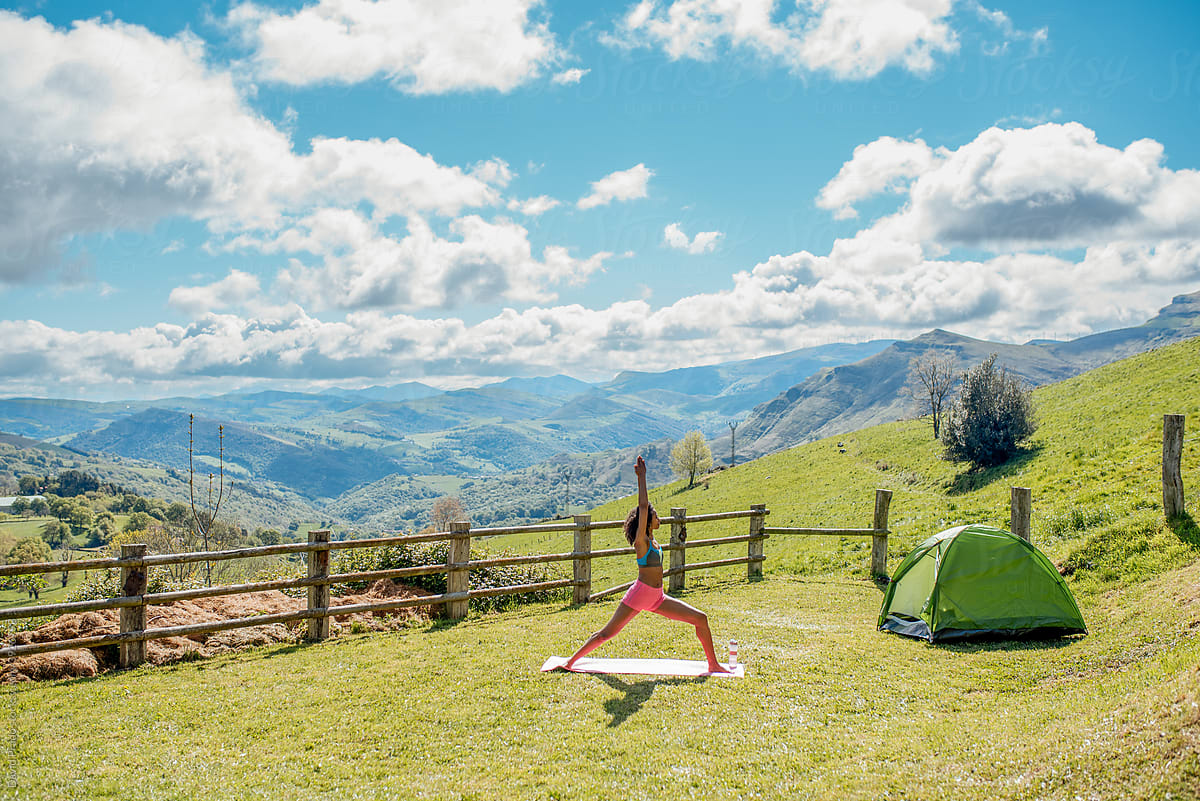 Woman doing yoga near tent in mountains