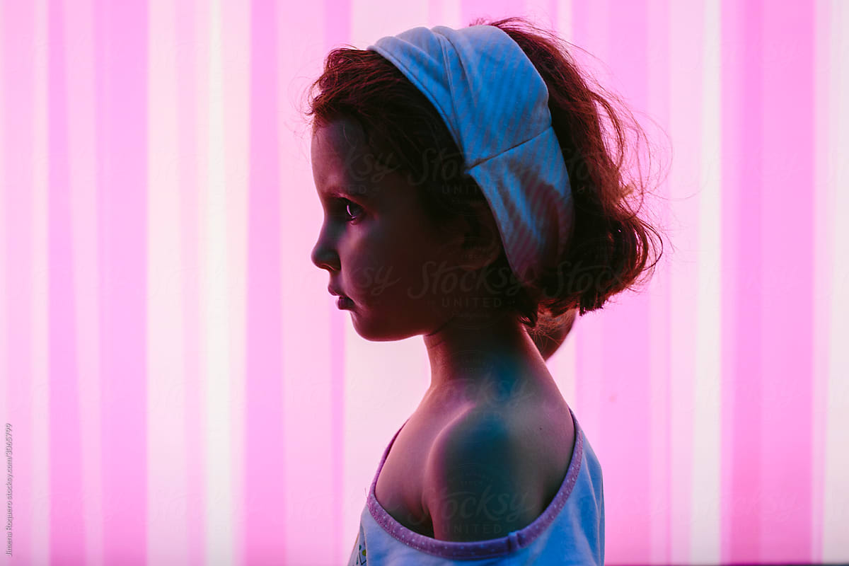 Portrait of a little girl silhouette over pink neon lightened background