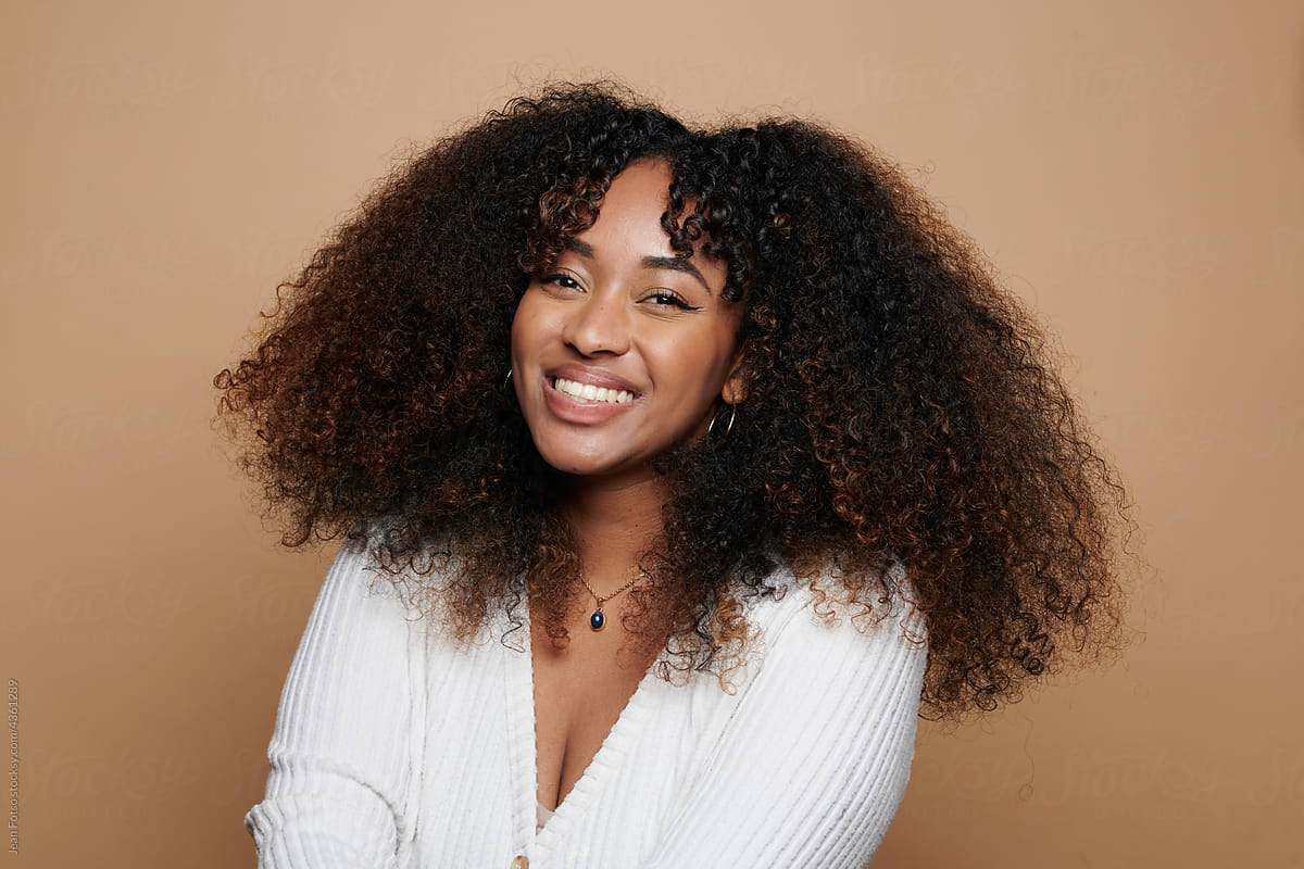 Black Curly Haired Woman smiling In Studio