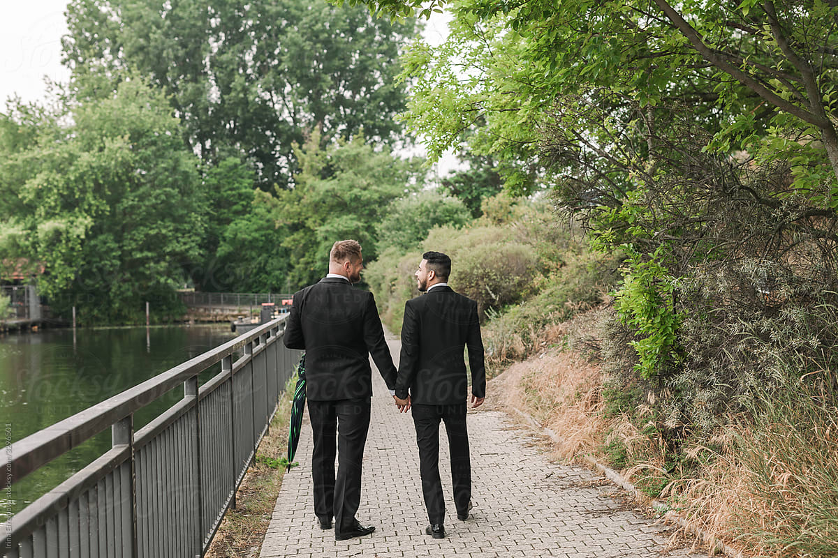 Two grooms walking by the river
