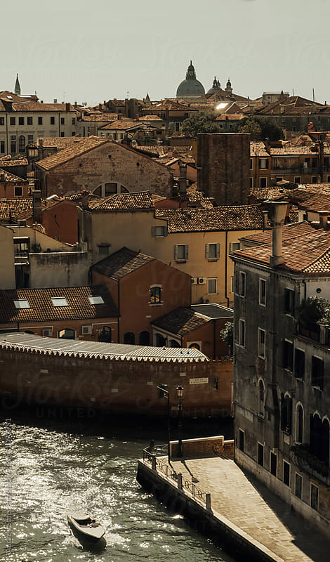 Aerial view of Venice with old rustic houses,boat canals and church towers across city.