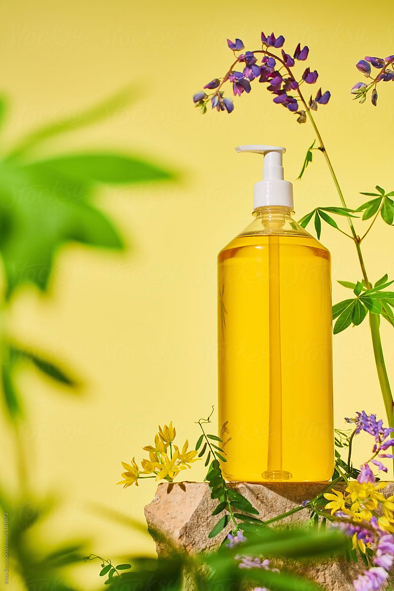 A bottle of liquid yellow soap stands in flowers