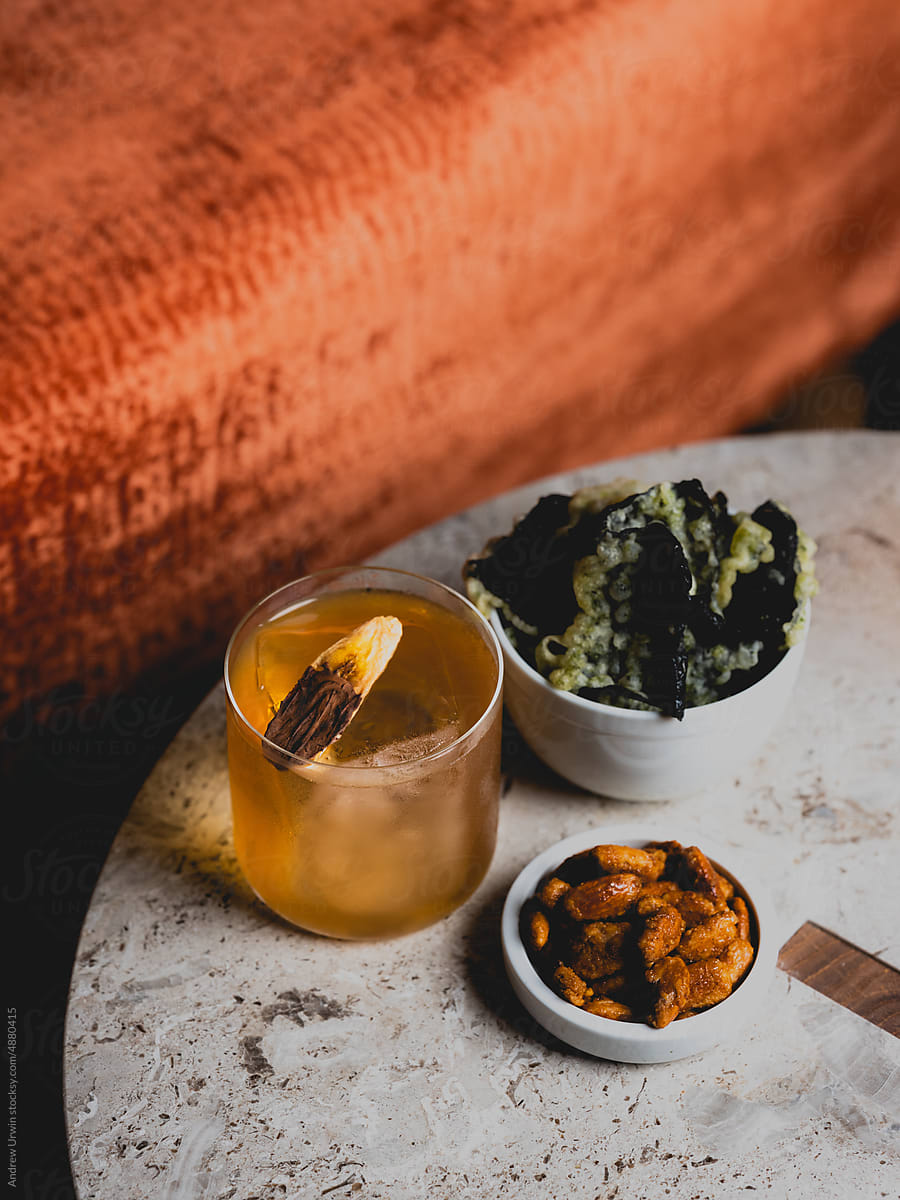 Whiskey cocktail and seaweed crisps and nuts