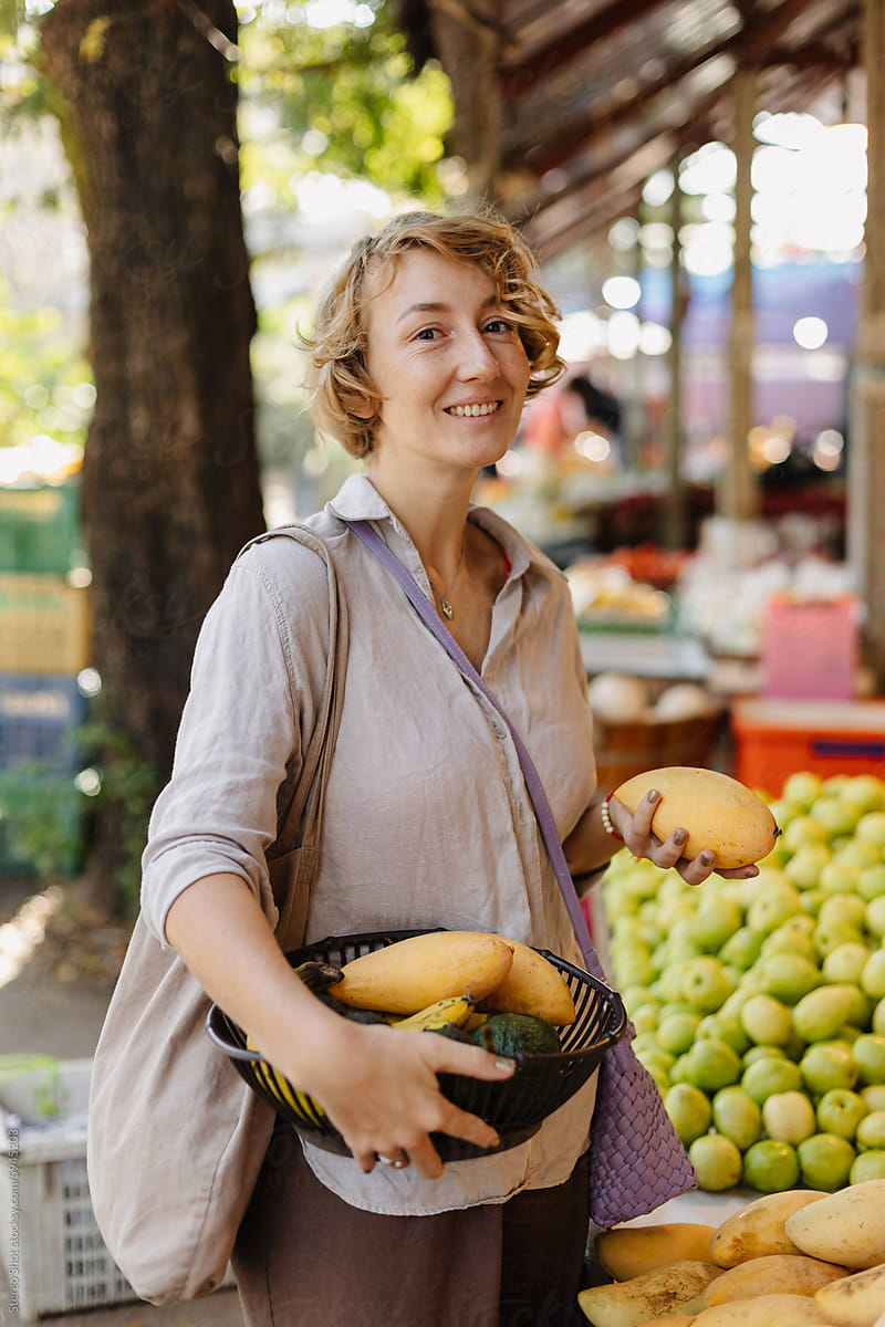 Smiling woman buying mangoes at local market