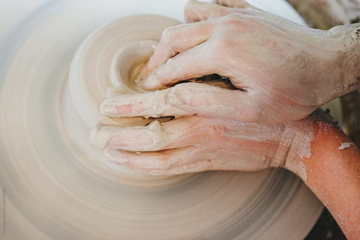 Dirty potter\'s hands making a ceramic just on a turning wheel