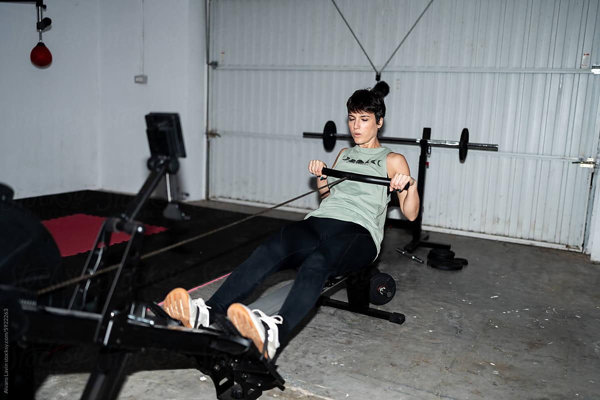 Woman Exercising on Rowing Machine in Home Gym