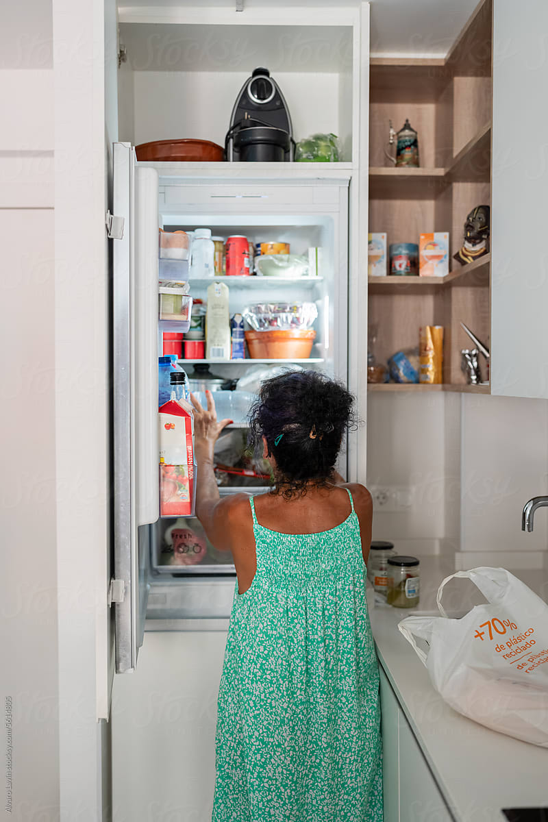 Woman with open fridge at home.