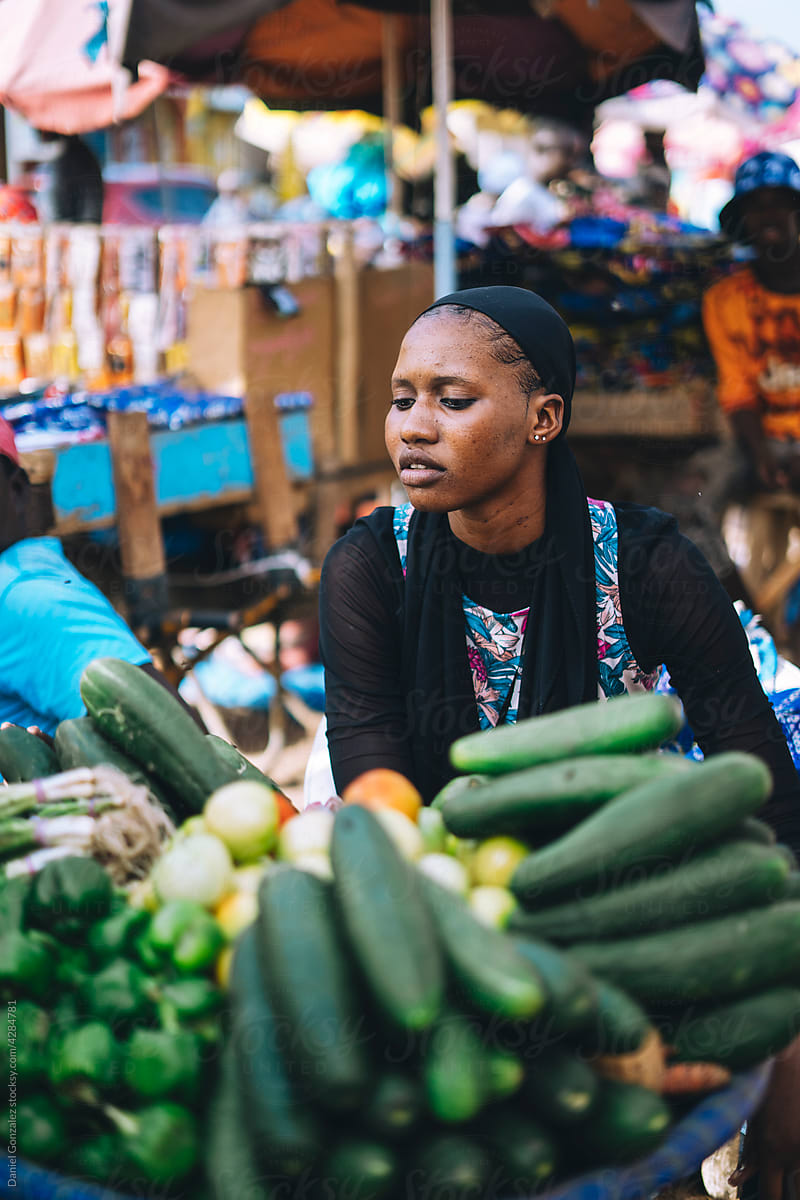 African seller examining vegetables on stall