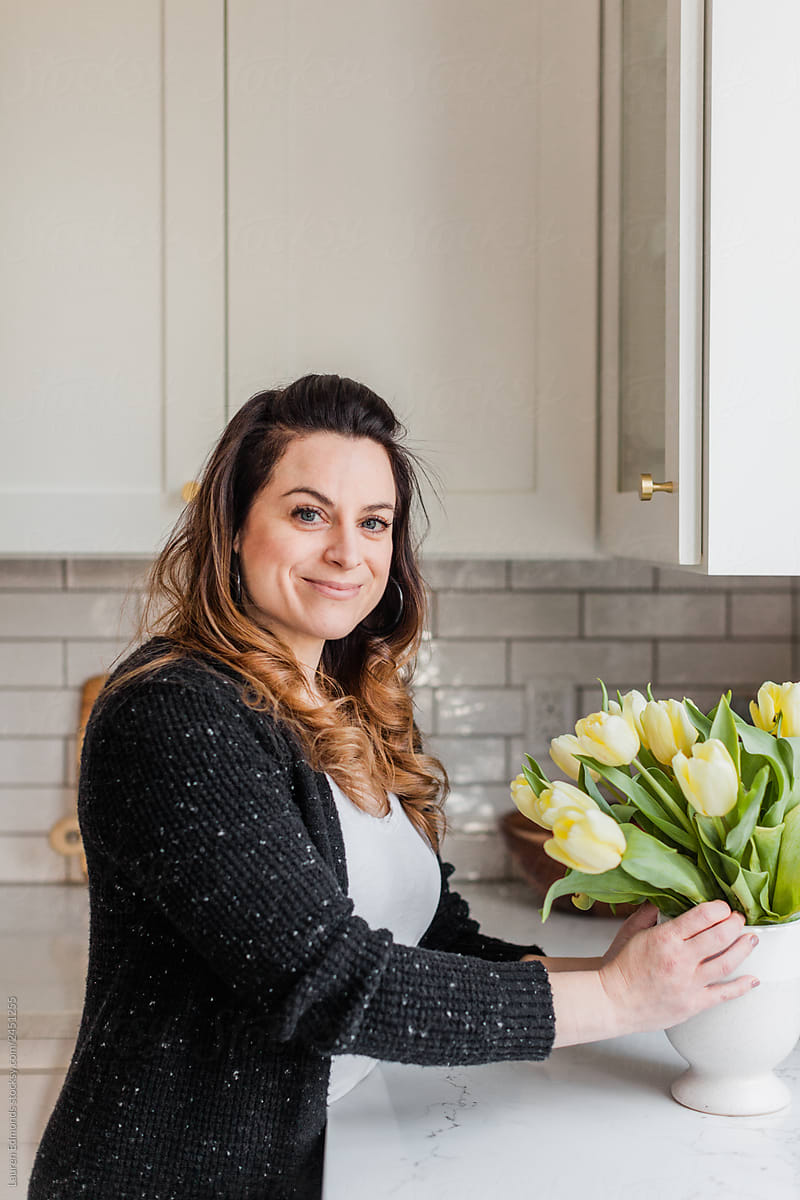 Woman arranging yellow tulips on kitchen counter