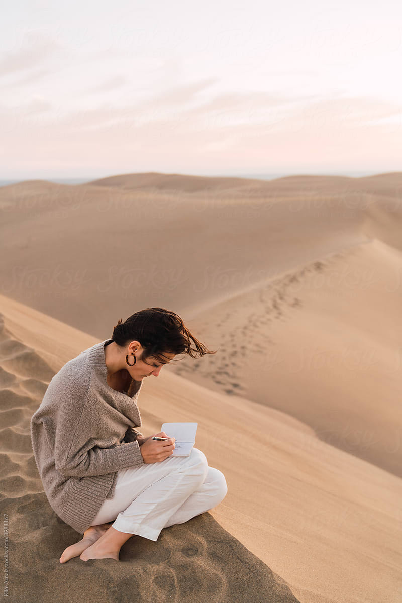 Woman with notebook sitting on sand