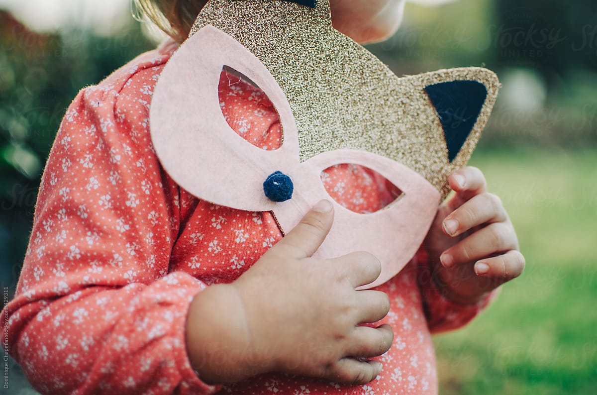 Close up of little girl holding glitter cat mask