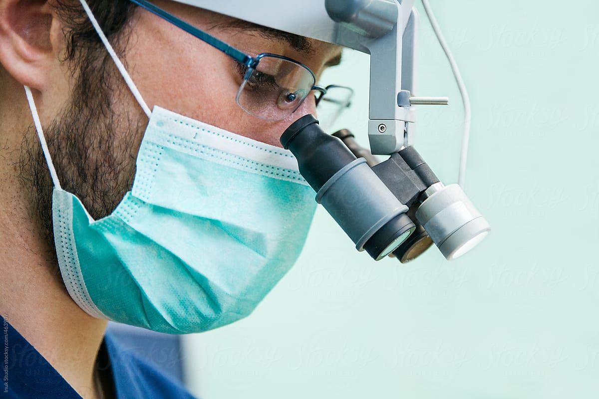 Portrait of a dentist with a surgeon mask and microscope glasses during a dental intervention