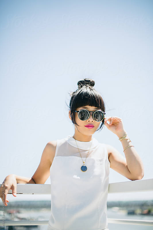 Stylish Asian young woman in white clothes and round sunglasses