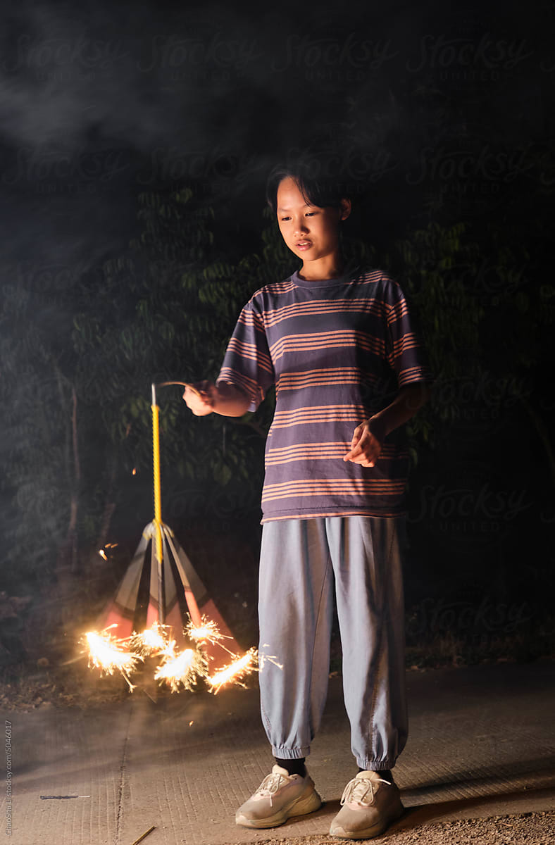 Asian girl, playing fireworks outdoors at night in nature