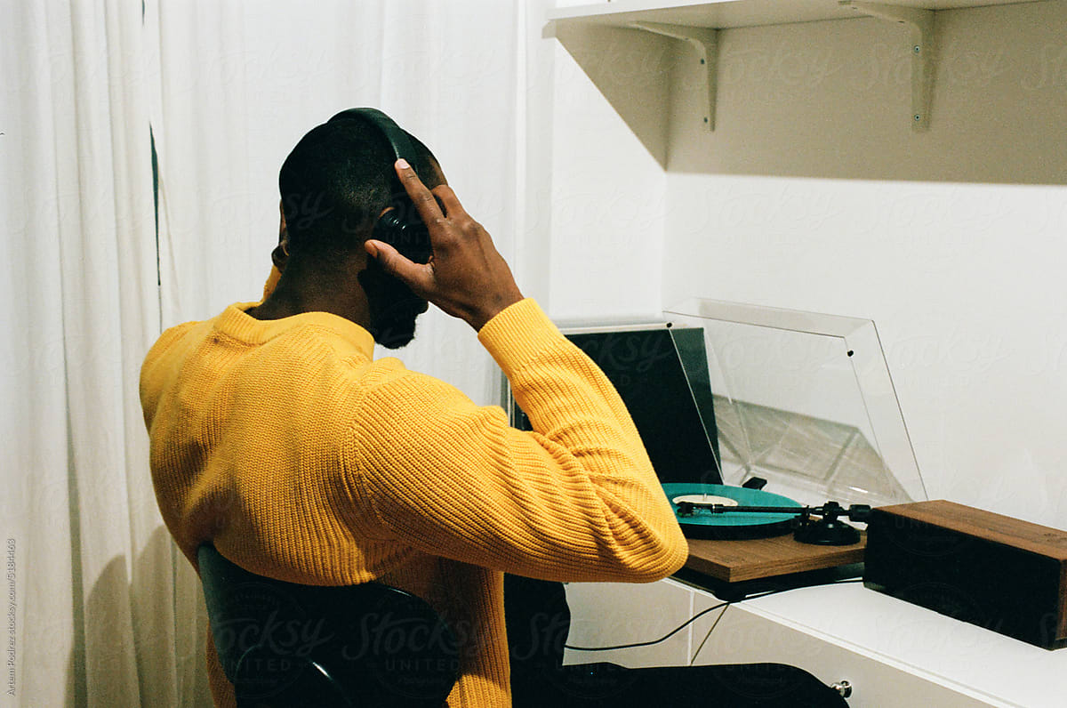 Film photo black man listens to music at home on a turntable