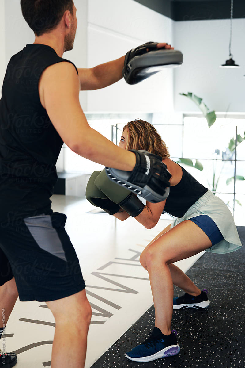 sportswoman in boxing gloves exercising with coach
