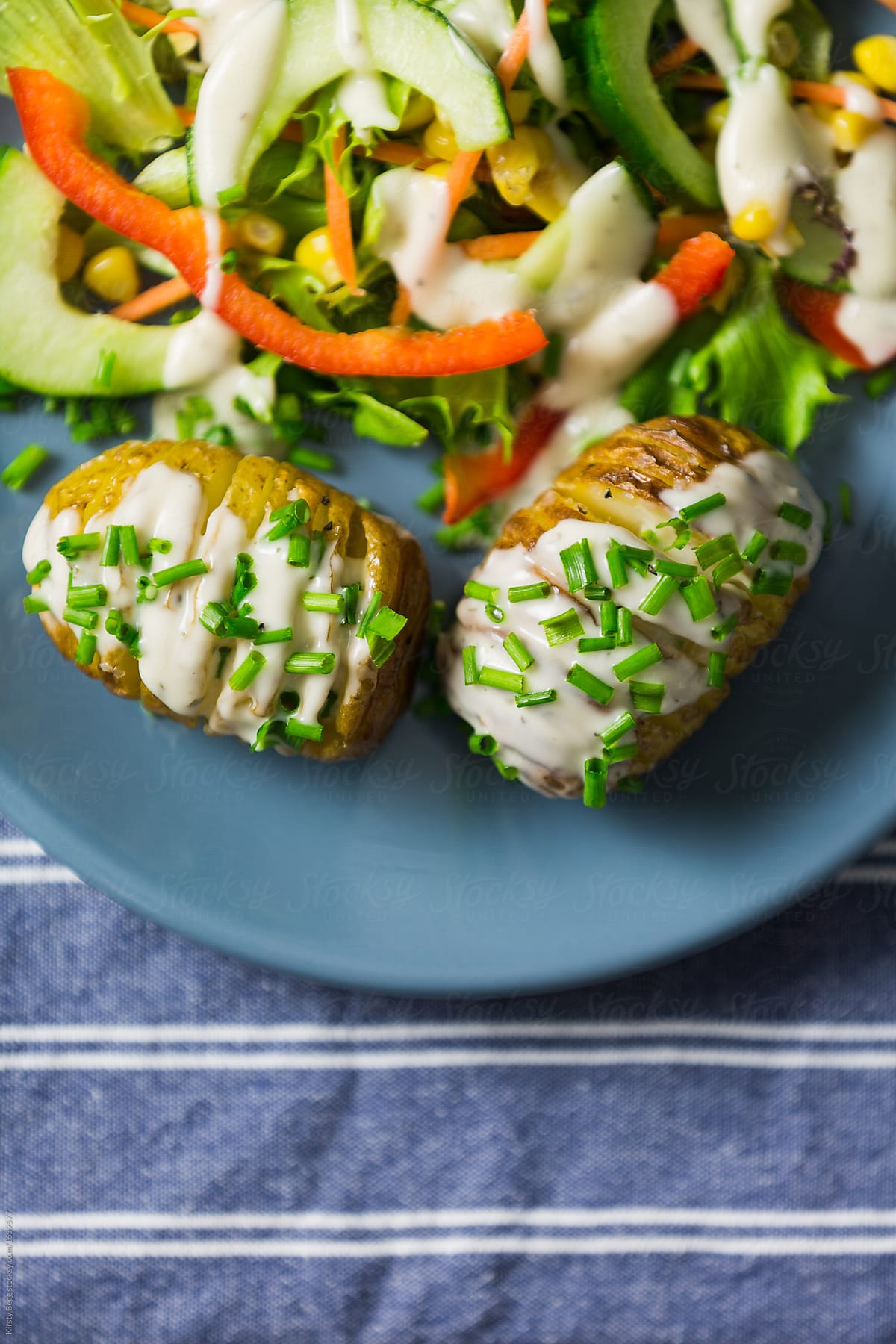 Close up of Hasselback potatoes with creamy dressing and chives