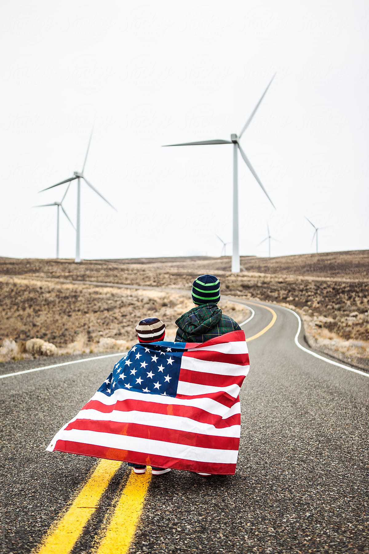 Two little boys with American flag standing near wind farm