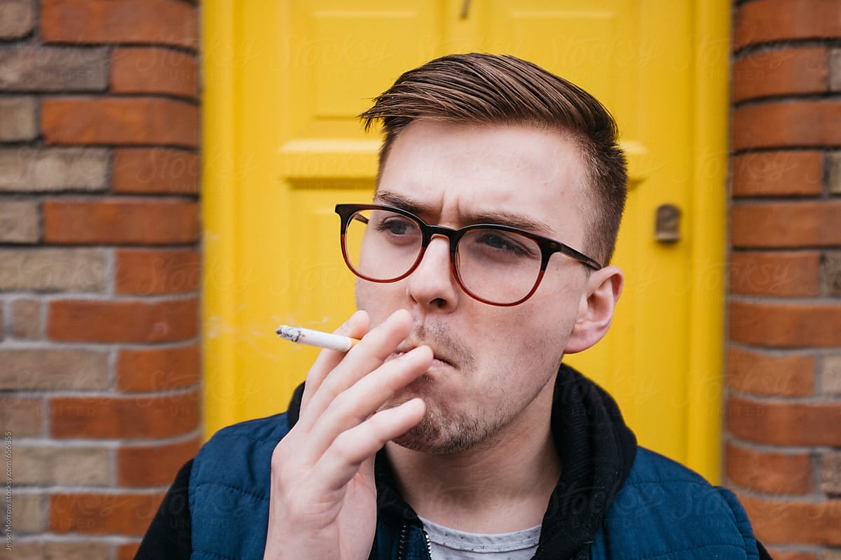 portrait of young adult male smoking in front of yellow door