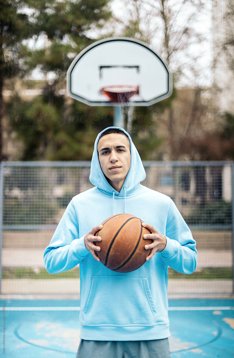 Young man holding basketball ball on a basketball court