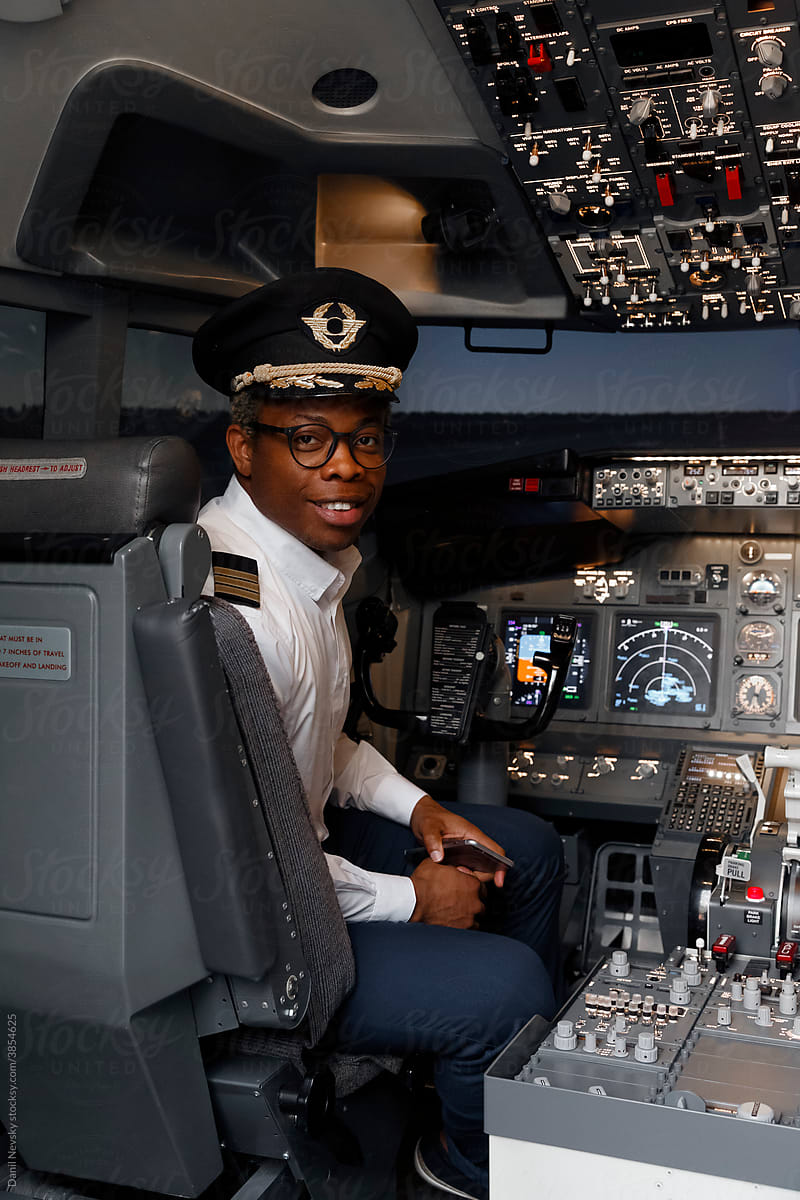 Cheerful black pilot in plane cockpit