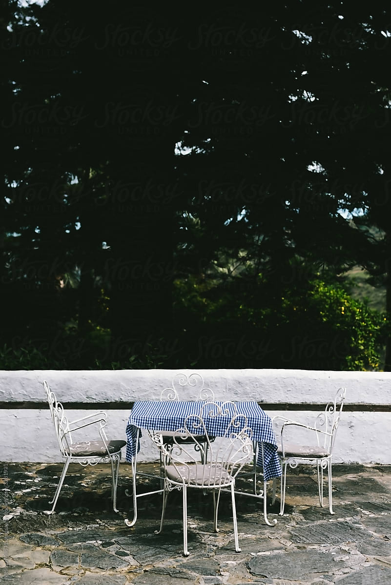 still life of a table with tablecloth with 3 white antique armchairs outdoors in spain