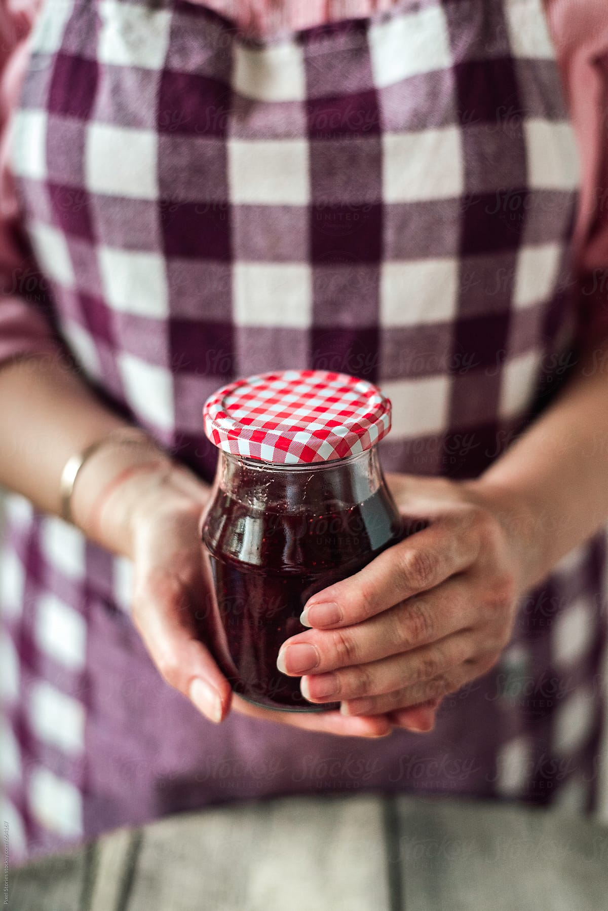 Hand holding jar filled with homemade strawberry jam