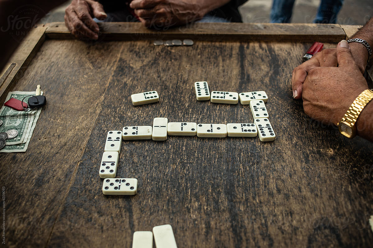 friends playing dominoes on a wooden table.