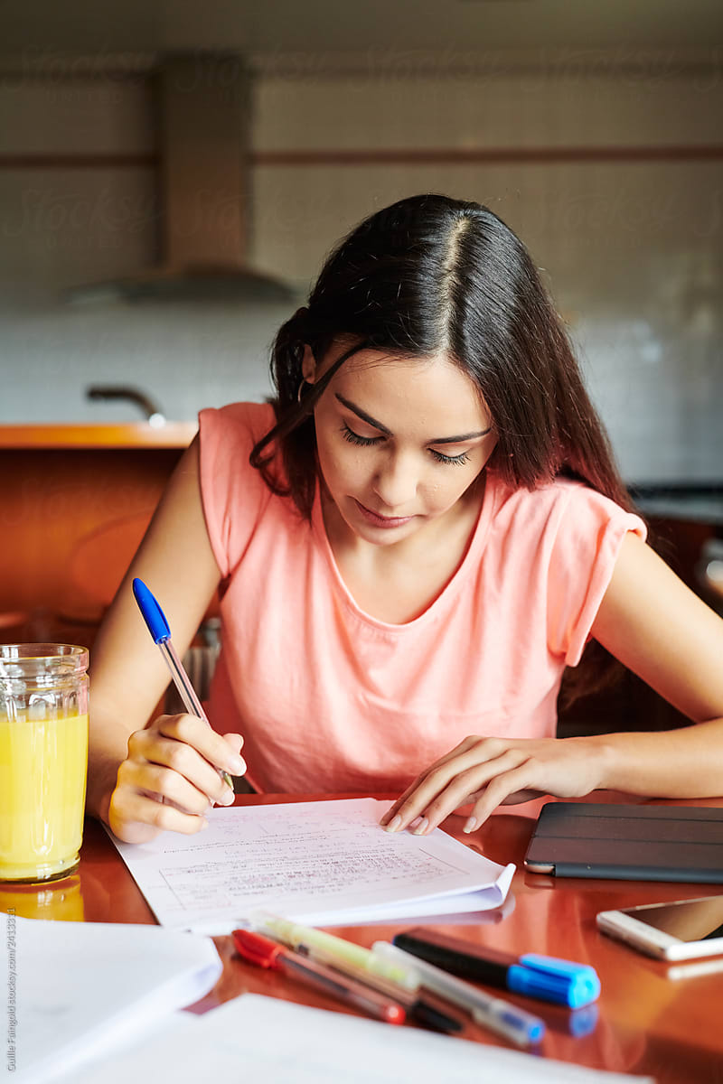 Focused woman studying at desk in kitchen