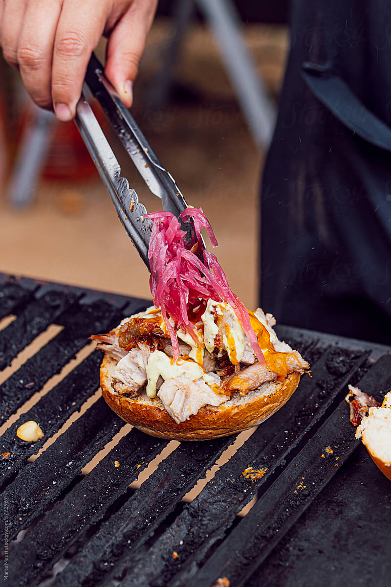Person making a pork and onion sandwich