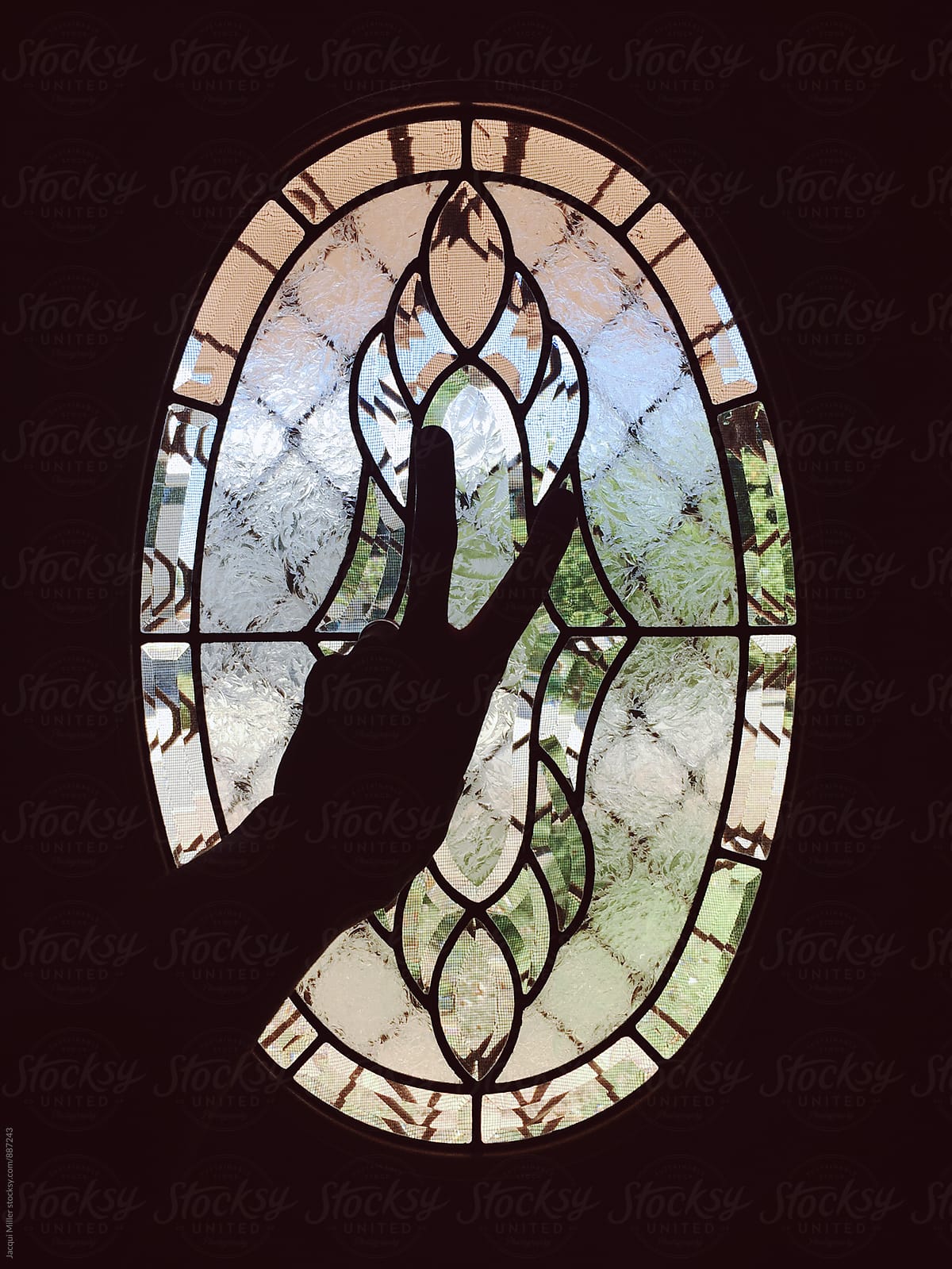 Silhouette of hand showing peace sign in front of oval window
