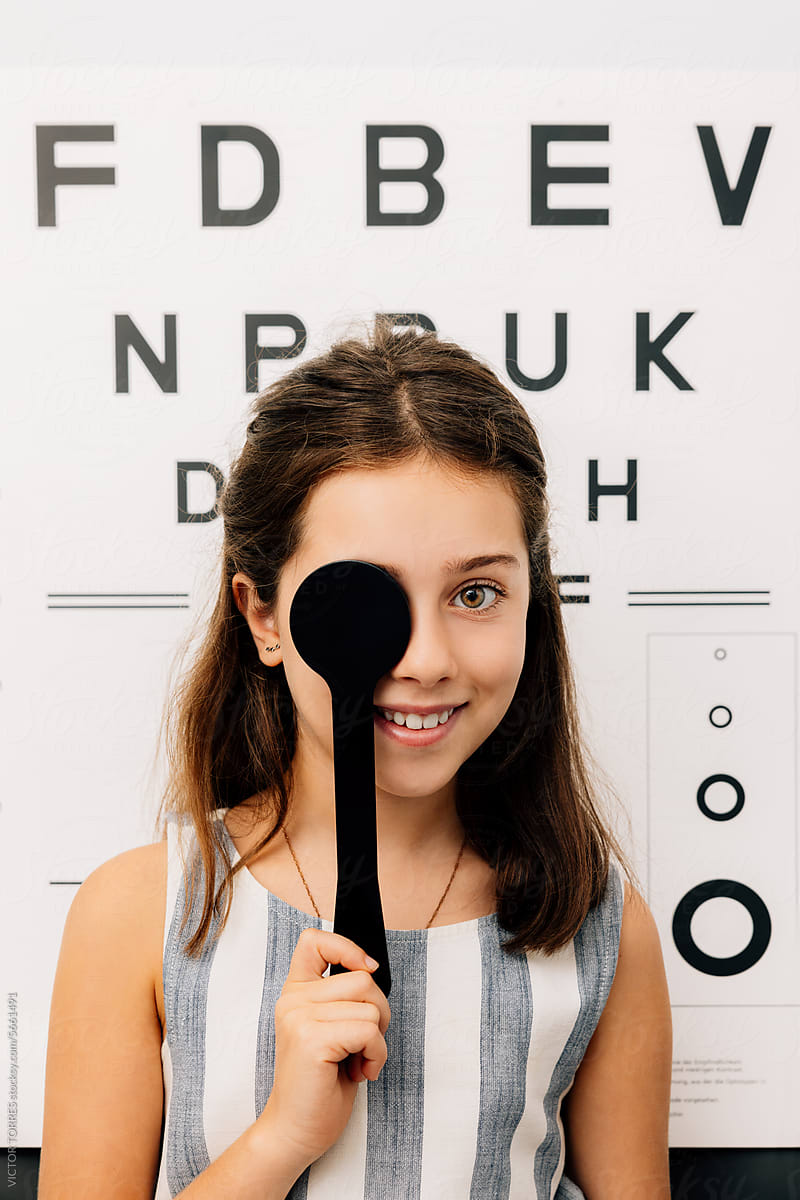 Happy girl standing near test chart with eye occluder
