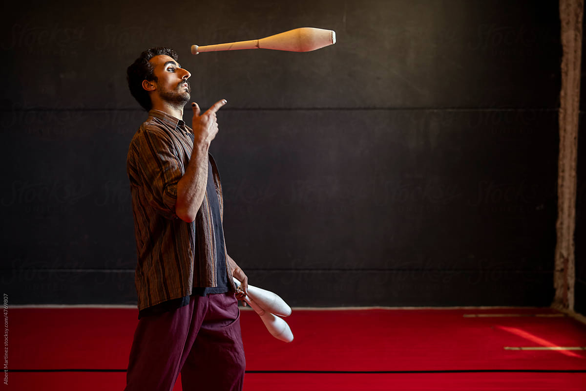 Attentive Hispanic man juggling clubs during rehearsal