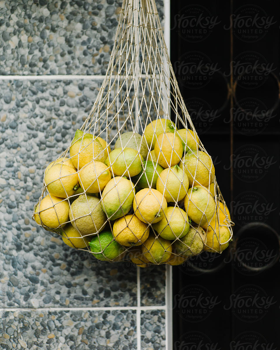 Tasty yellow lemons in string bag selling in shop