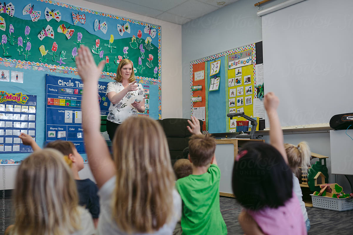 Kindergarten kid raising hand in classroom