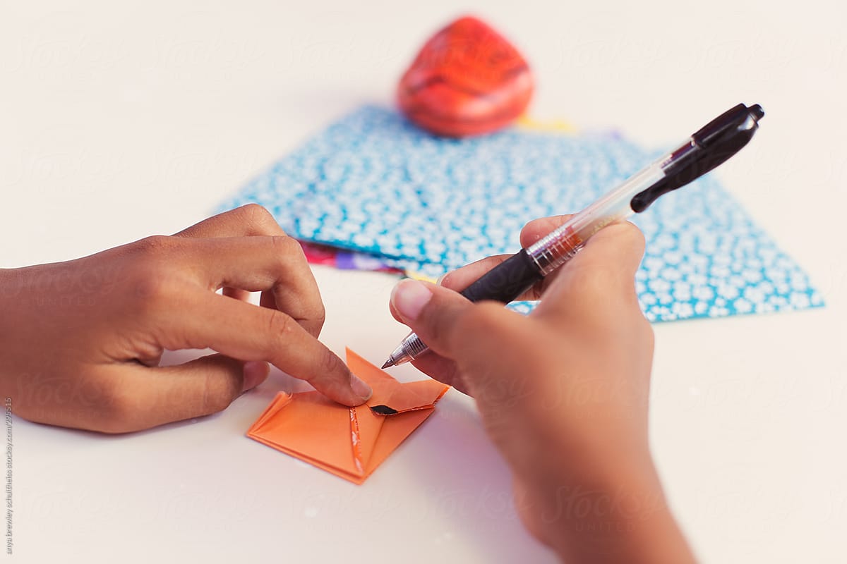 Young girl drawing eyes onto an origami fox