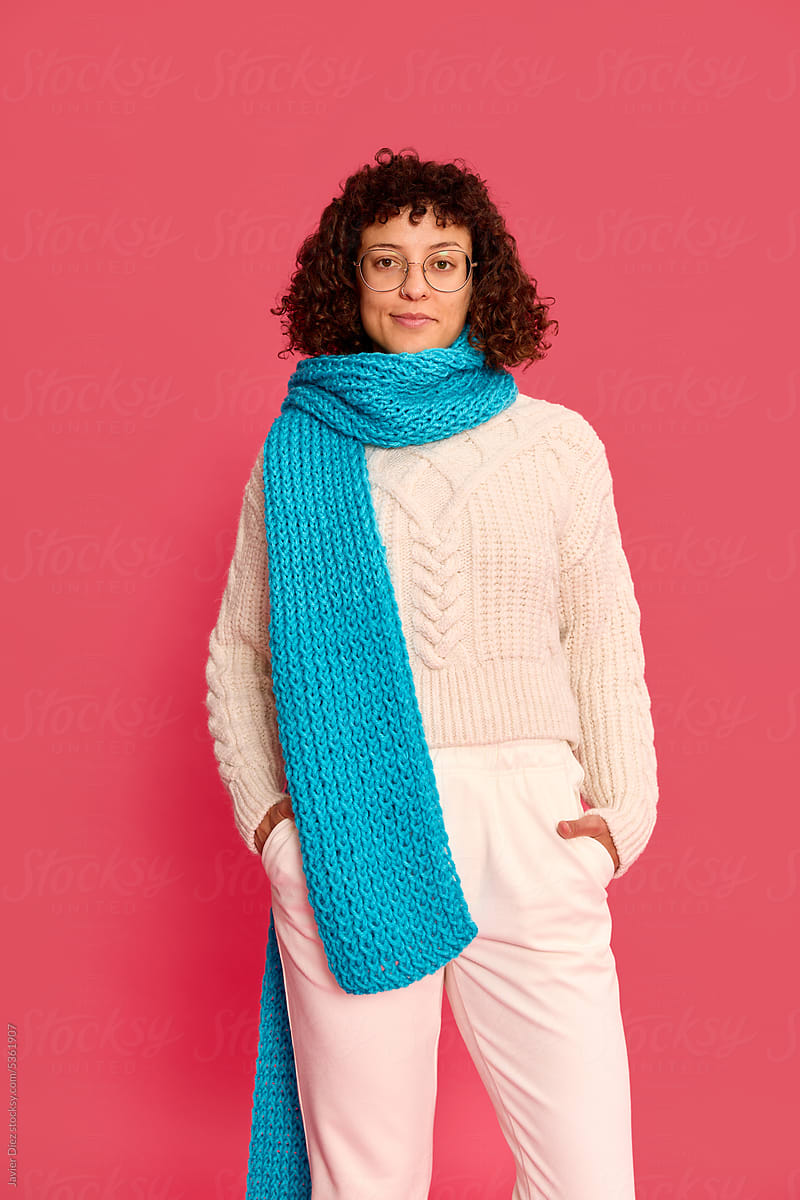 Joyful woman standing with blue scarf and looking at camera in s