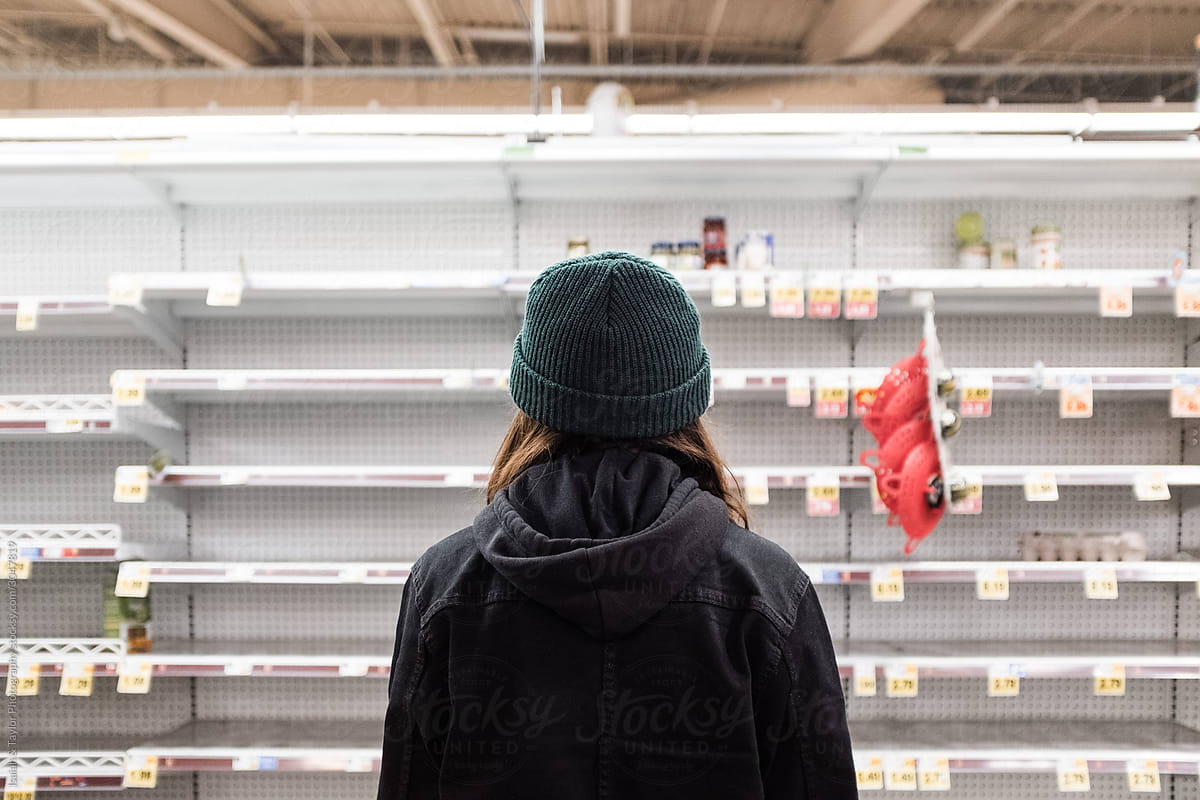 Person shopping alone staring at empty grocery store shelves during the Coronavirus pandemic