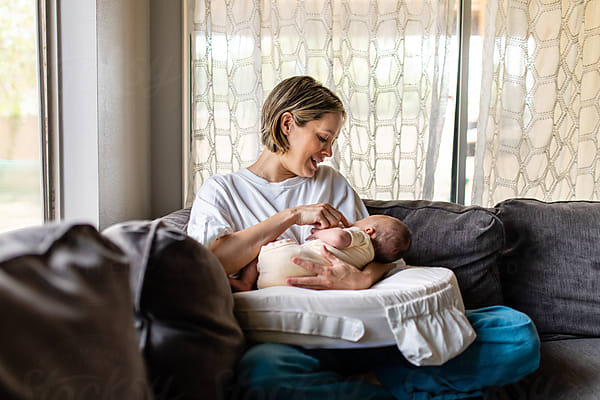 New Mother Does Yoga On A Mat While Nursing Child by Stocksy Contributor  McKinsey Jordan - Stocksy