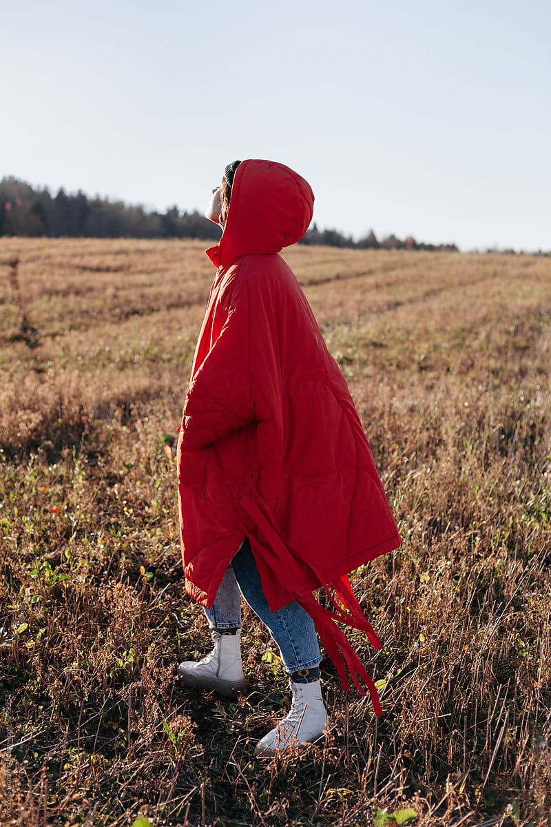 Woman in red warm coat walking in field