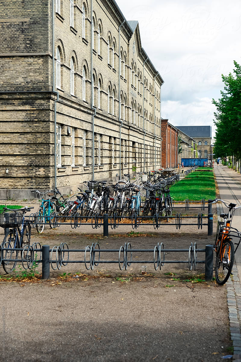Multiple bicycles parked adjacent to a building on a cloudy day