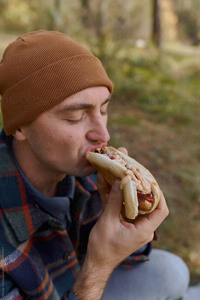 man on camping trip eats dinner hot dog