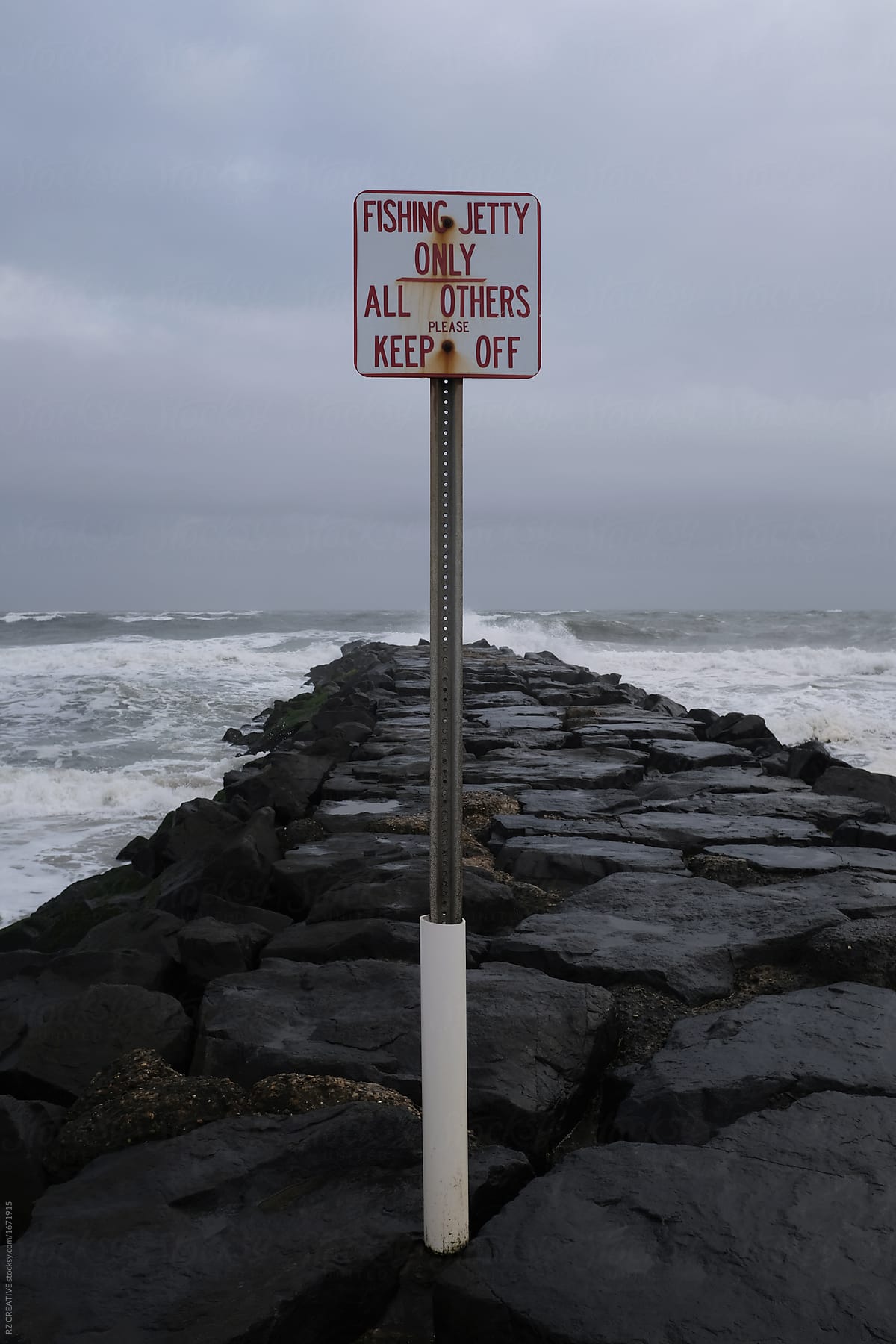 Sign on rocks with dark fall weather.