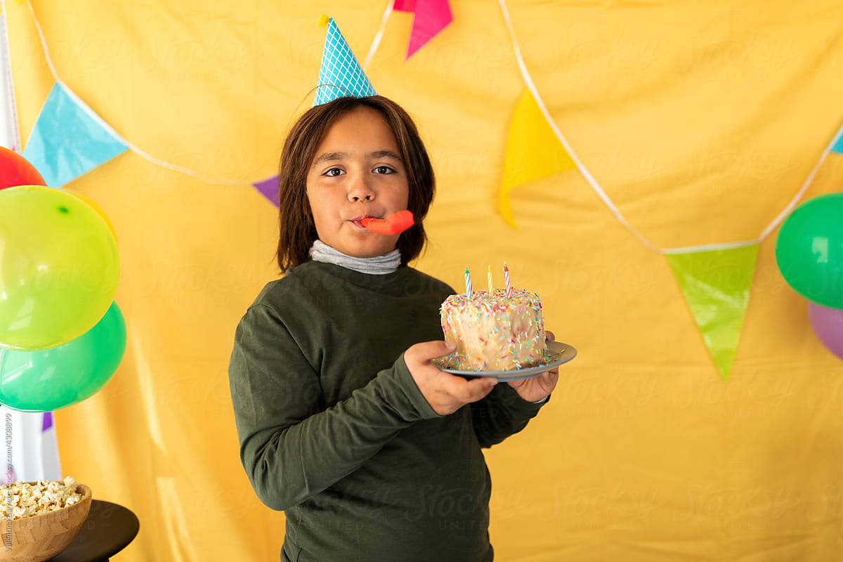 Teen boy with birthday cake and noisemaker