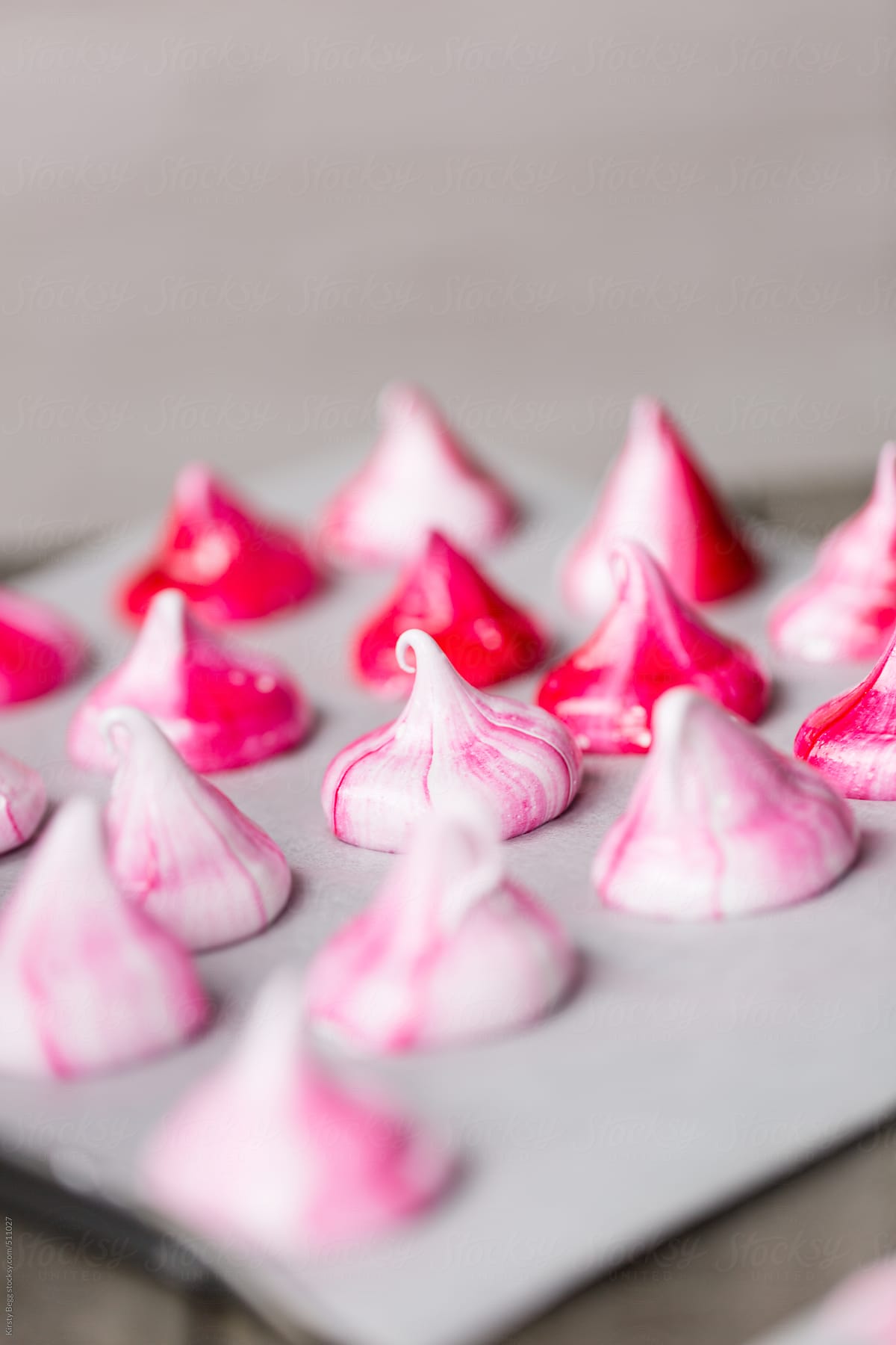 Pink meringue kisses on baking sheet